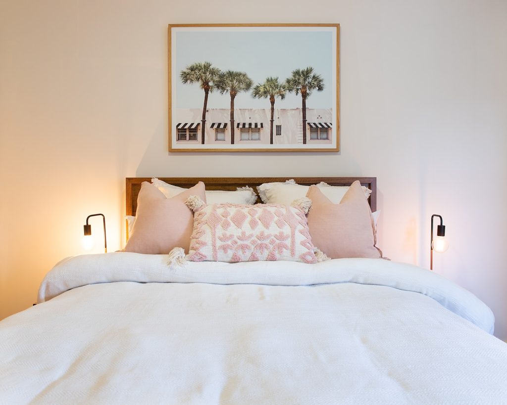 a bed with a white comforter and pink pillows